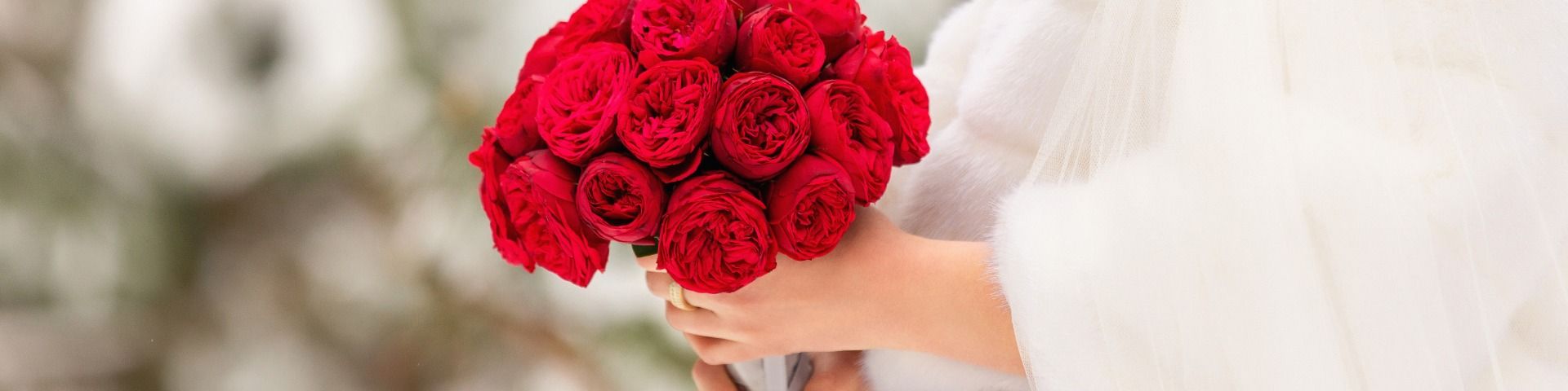 Warm gekleidete Braut mit Brautstrauss aus roten Rosen