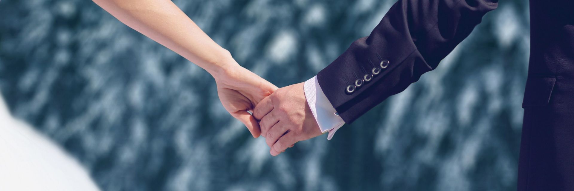 Brautpaar gibt sich die Hand mit Schnee im Hintergrund